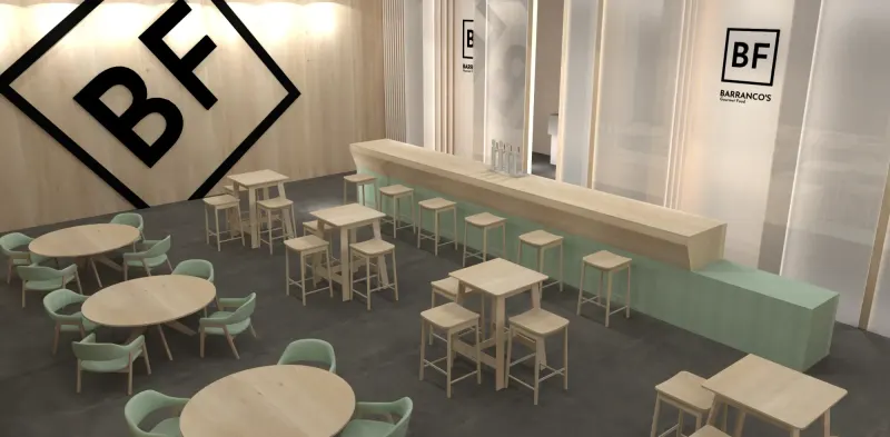 Zona de degustación de un stand gourmet: barra de madera, mesas altas y área de mesas con butacas