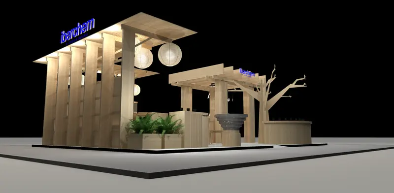 El mismo stand de noche desde la esquina: lamas verticales de madera, paneles traslúcidos, rótulo retroiluminado y farolillos encendidos